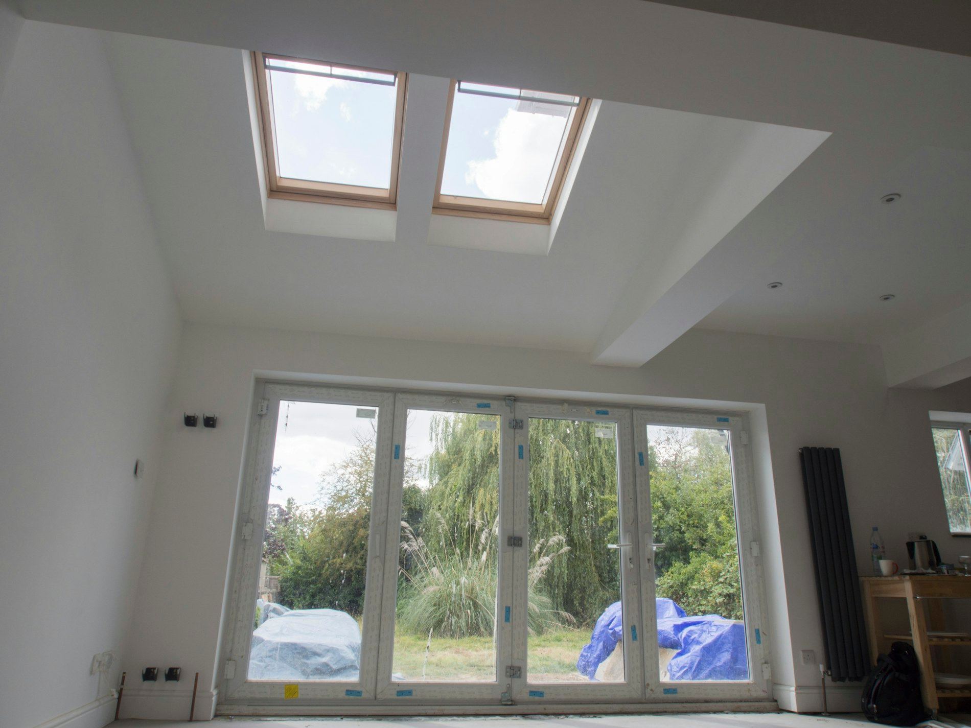 Bright home extension with skylights and bi-fold doors opening to a garden.