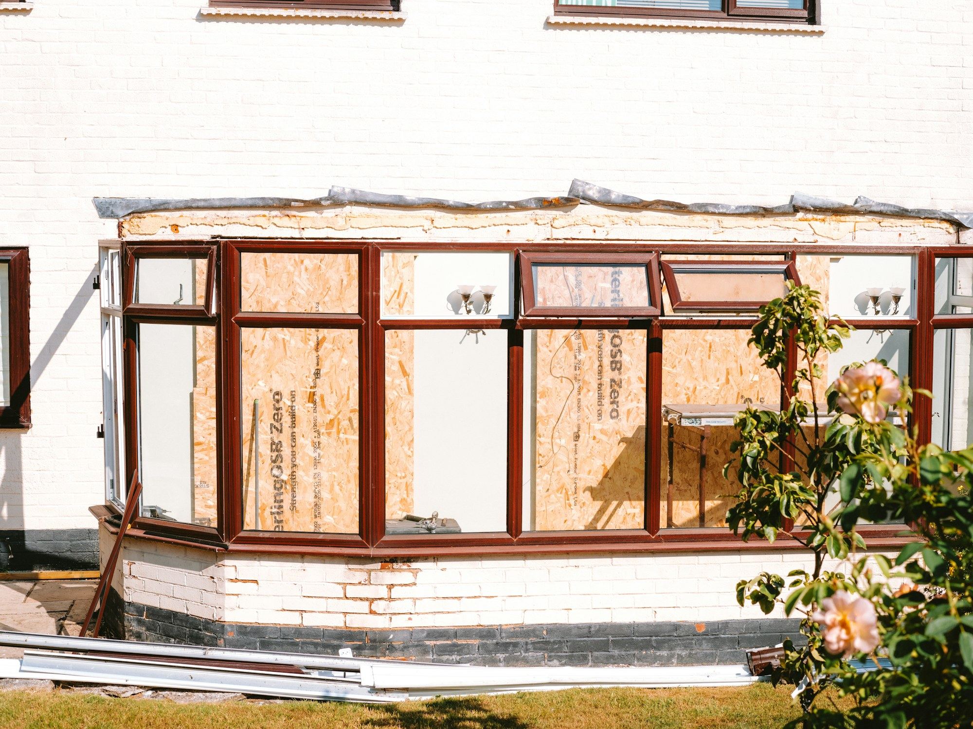Conservatory extension under construction with boarded-up windows.
