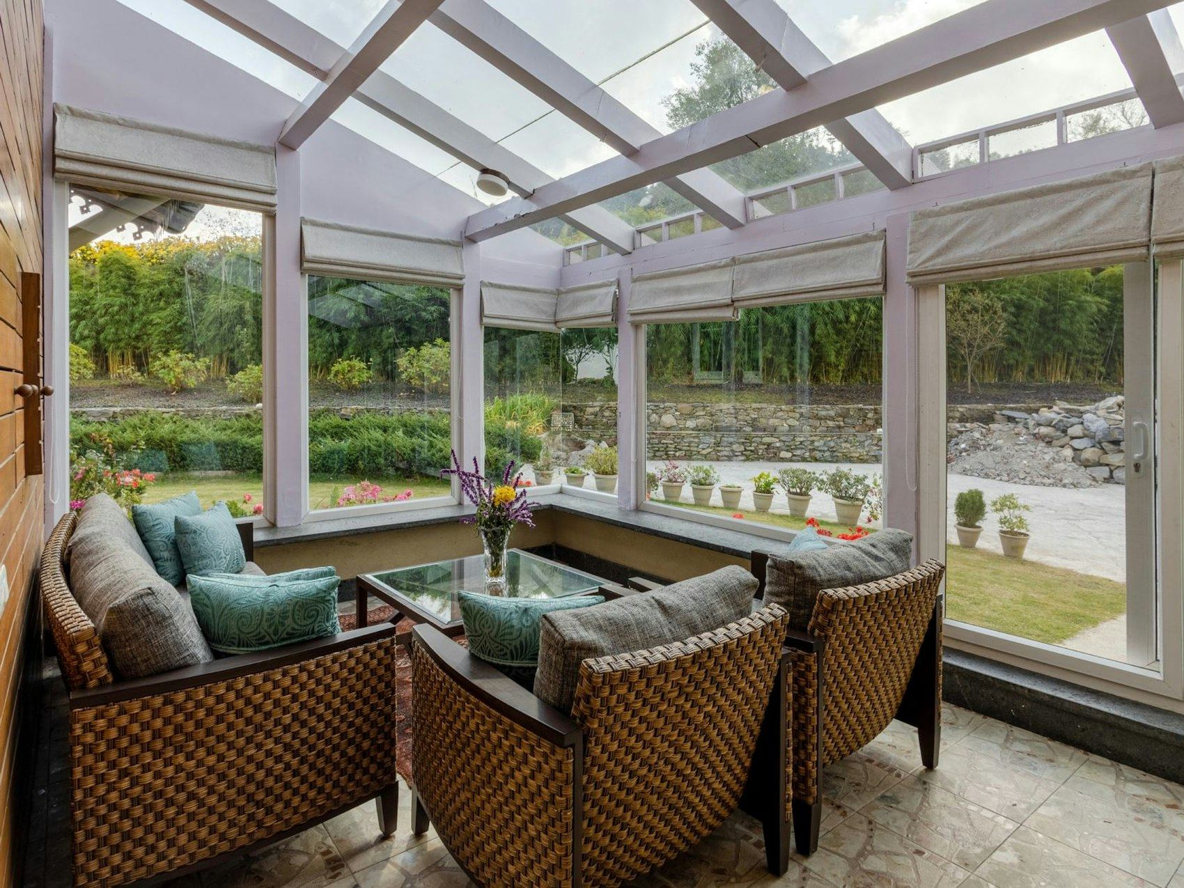 Sunlit conservatory interior with wicker armchairs overlooking a garden