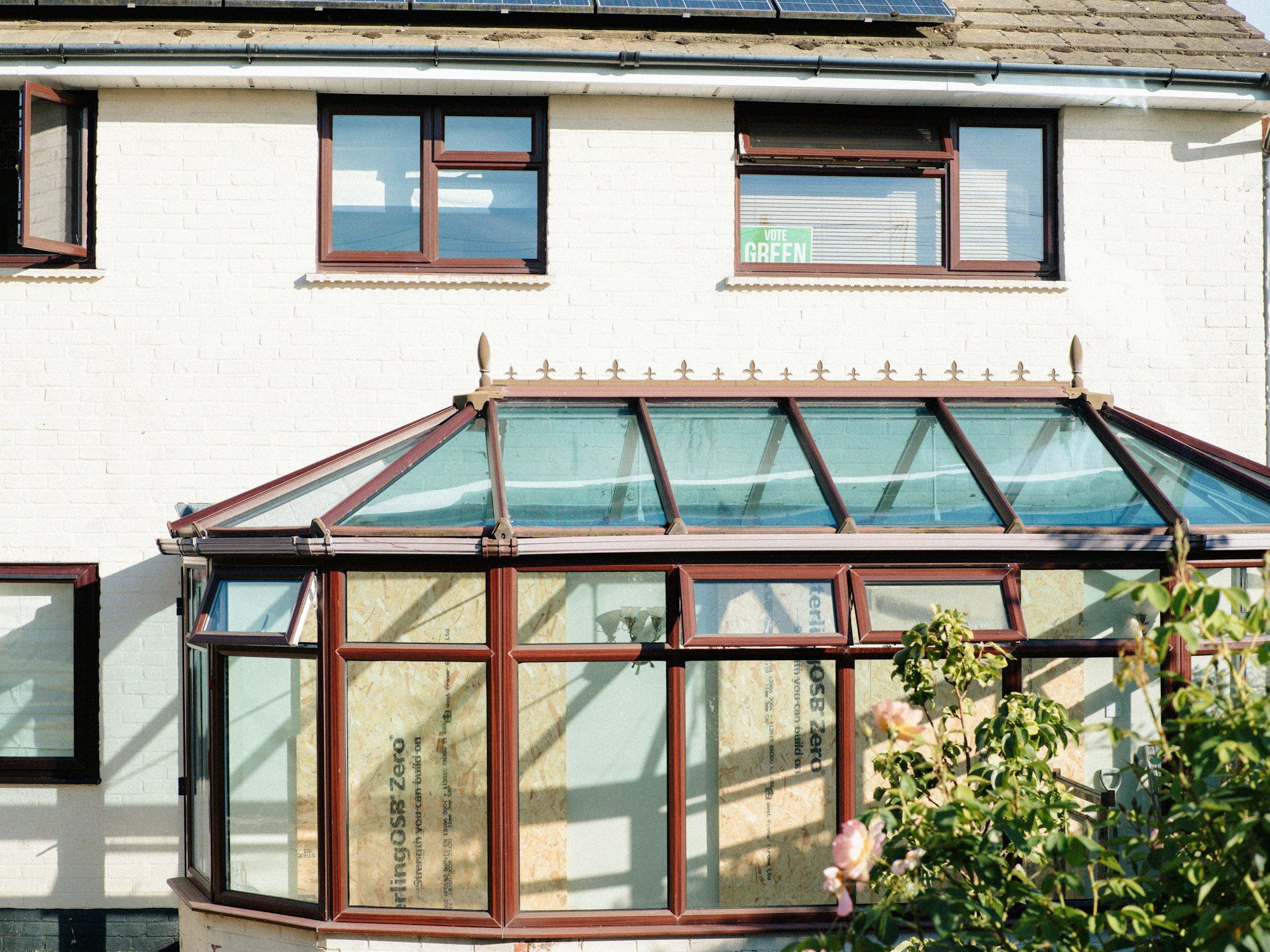 White house exterior with a brown-framed conservatory attached to the rear